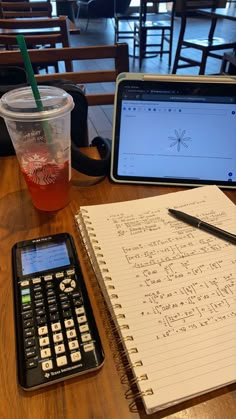 a notebook and calculator on a table with a cup of tea next to it