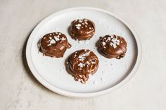 four chocolate covered desserts on a white plate