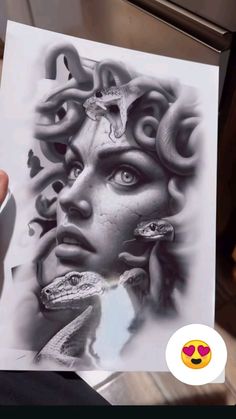 a person holding up a piece of paper with an image of a woman's face and snake on it