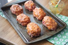 some meatballs are sitting on a baking tray next to a glass of orange juice