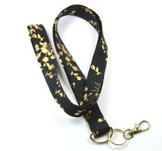 This cute lanyard has gold flowers on black. It is perfect for any occasion. You can leave me a convoy if you need a different size. You can have a wardrobe of lanyard to match your outfit. This lanyard is made of soft 100% cotton fabric to give a comfortable feel around your neck. This lanyard is easy to take care. You can spot clean and throw in a washer and hang dry. If you want you can iron and it is ready to use. These lanyards are perfect if you have metal allergy. Each of these lanyards w Adjustable Black Lanyards For Personal Use, Black Lanyard With Key Leash As Gift, Black Lanyard With Key Leash For Personal Use, Cute Lanyard, Cute Lanyards, Black Lanyard, Fabric Lanyard, Golden Flower, Have Metal