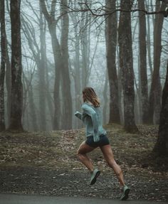 a woman running in the woods on a foggy day