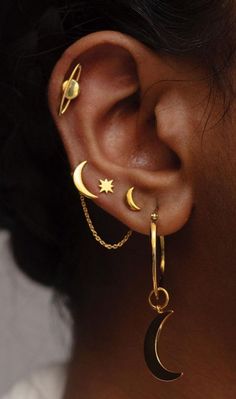 a woman wearing gold ear piercings with crescent and stars