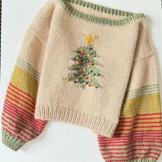 a knitted sweater with a christmas tree on the front and colorful stripes around it