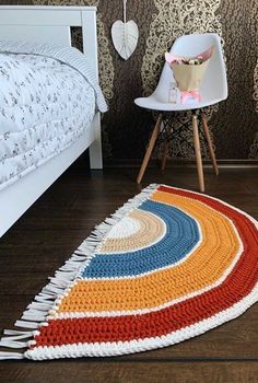 a crocheted rug on the floor next to a white chair and bed in a bedroom