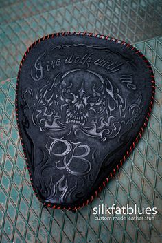 a black guitar pickle with a skull on it's back and red stitching around the edges