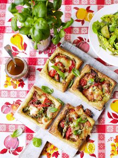 four square pizzas sitting on top of a red and white checkered table cloth