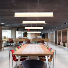 an empty conference room with tables and chairs in the center, lights hanging from the ceiling