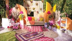 an outdoor area decorated in bright colors with surfboards and rugs on the ground