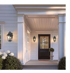 the front door of a white house with two large lanterns on it's side