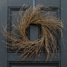 a wreath on the front door of a house that has been decorated with dried twigs