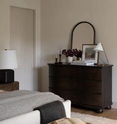 a bedroom with a bed, dresser and mirror on the side table in front of it