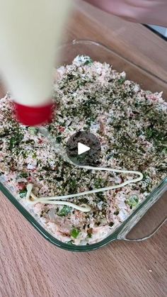 someone is mixing food in a glass dish on the table with a red and white spatula