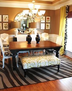 a dinning room table with chairs and a bench in front of a large mirror