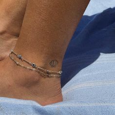 a woman's foot with a tattoo on it and a chain around the ankle