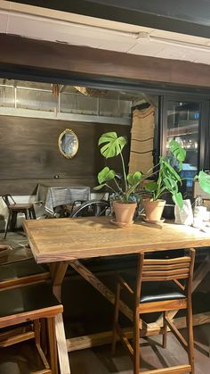 a wooden table sitting in front of a window with potted plants on top of it