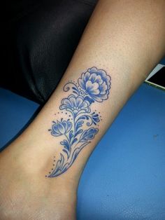 a woman's foot with a blue flower tattoo on the left side of her leg