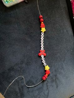 a necklace made out of plastic beads with letters and stars hanging from the side on a table