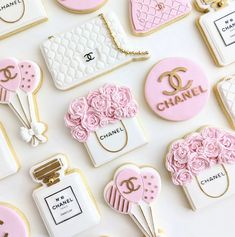 chanel cookies are arranged on a table with pink flowers and purses in them