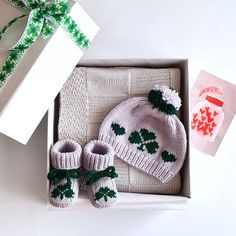 a baby's hat and booties are in a box with a green ribbon