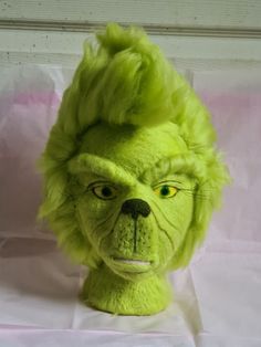 a green stuffed animal head on top of a white sheet