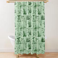 a green shower curtain with an image of animals and plants on it in front of a bathtub