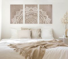 a white bed topped with pillows and two pictures on the wall above it's headboard