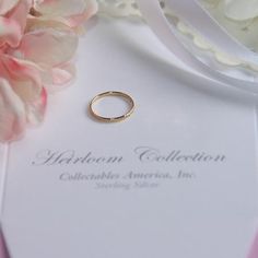 a wedding ring sitting on top of a white card next to pink and white flowers