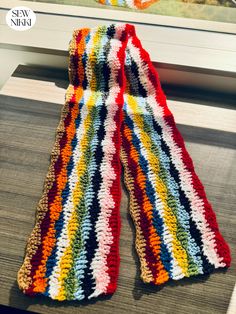 a multicolored crocheted scarf sitting on top of a window sill