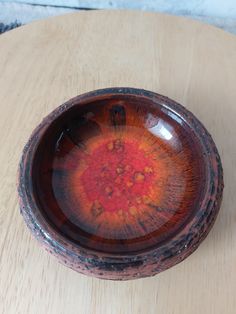 a brown and orange bowl sitting on top of a wooden table