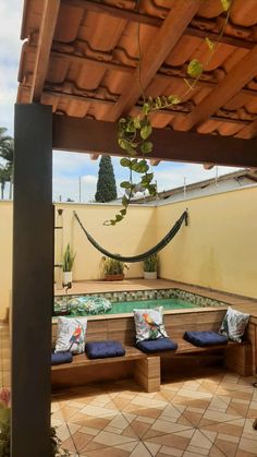 an outdoor hot tub with hammock and pillows on the floor next to it