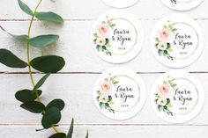 four personalized wedding coasters with pink flowers and greenery on white wooden background