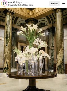 there are many vases with flowers in them on the table at the reception room