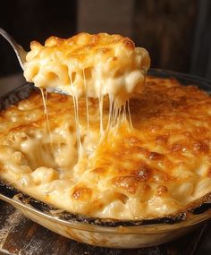 a close up of a person holding a spoon with macaroni and cheese on it