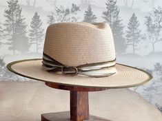 Introducing our Glazed Toyo Straw Hat with Flat Brim in Natural! This stylish hat features a beautiful Ivory and Olive 100% silk trim with an antique brass finding. Made from high-quality materials, this hat is perfect for adding a touch of style to your resort and everyday outfits. Stay cool and fashionable with this must-have accessory! One of a kind. Headsize is Medium 22 1/2" Luxury Handmade Wide Brim Hat, Handmade Cream Fedora With Short Brim, Cream Bohemian Toquilla Straw Hats, Elegant Cream Toquilla Straw Hat Band, Cream Panama Hat With Short Brim For Country Events, Luxury Cream Flat Brim Hat, Bohemian Cream Panama Hat With Curved Brim, Luxury Cream Hat With Short Brim, Elegant Beige Hats For Country Events