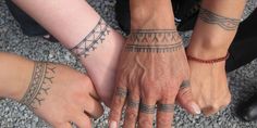 three people holding hands with tattoos on them