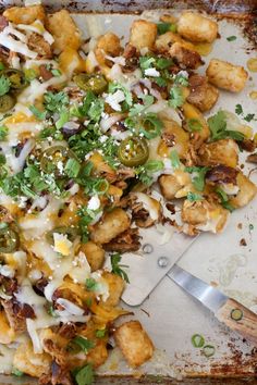 a pizza sitting on top of a metal pan covered in toppings next to a knife