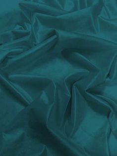 a close up shot of a teal colored fabric with very soft folds and wrinkles