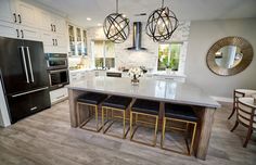 a large kitchen with an island in the middle and two pendant lights hanging from the ceiling