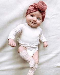 a baby wearing a turban and leg warmers laying on a white sheet