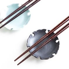 two chopsticks are sitting next to each other in front of some bowls with chop sticks sticking out of them