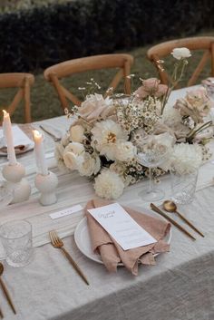 the table is set with white flowers and place settings for an elegant dinner or reception