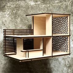 a model of a house made out of plywood and wood, on a concrete wall