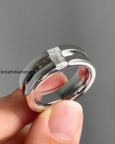 a person holding a wedding ring with a diamond in it's center and the other hand