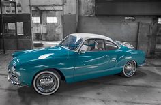 an old blue car parked in a garage