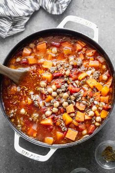 a pot filled with stew and vegetables on top of a counter next to some spices