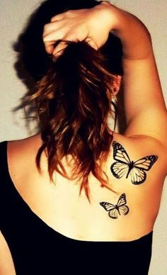 a woman with two butterflies on her upper arm and shoulder, behind her is a white wall