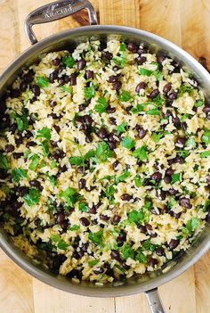 a pot filled with rice and black beans on top of a wooden table next to a knife