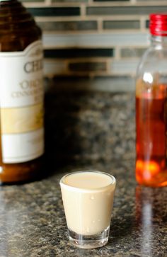 a shot glass filled with liquid sitting on top of a counter next to two bottles