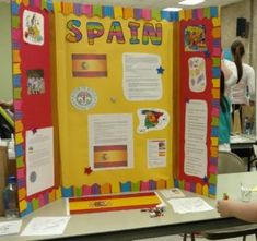 a bulletin board with spanish words and pictures on it, sitting at a table in a classroom